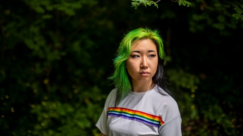 A photo of Mona Wang, a young woman with dyed green and purple hair, looking off camera