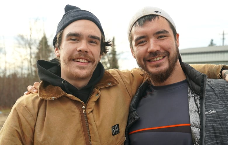 Two smiling men have their arms around each other. 