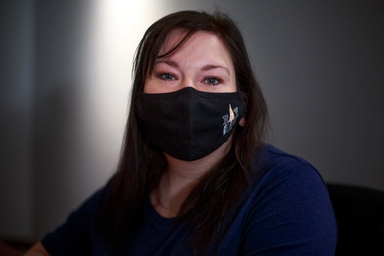 Portrait of Caryn Birch wearing a black mask. 