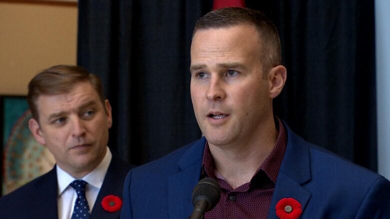 A man in a suit stands at a microphone