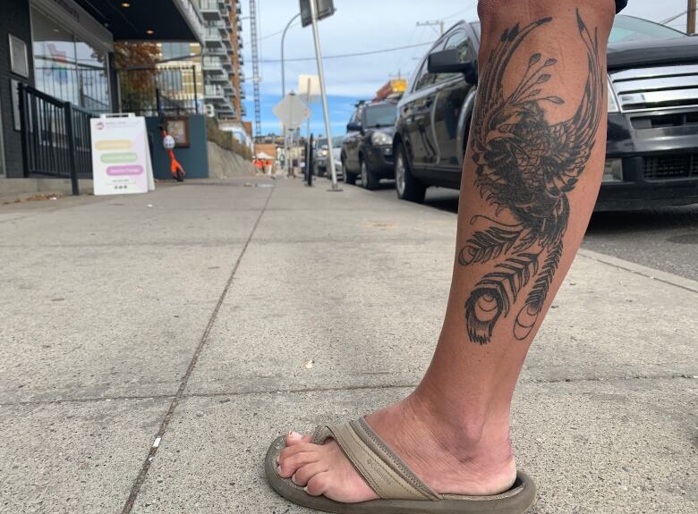 A dark blue tattoo of a mythical bird on a woman's calf.