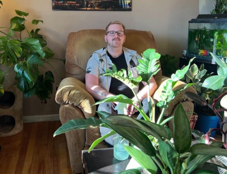 Man sits with plants around him.