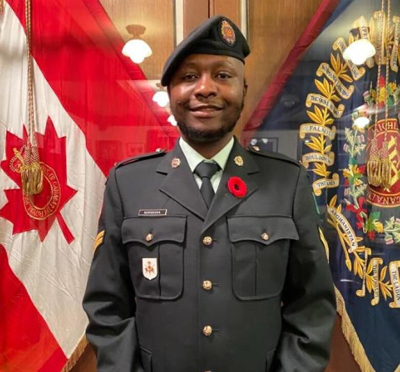 Soldier stands on guard before two service flags at the Cambridge Armoury.