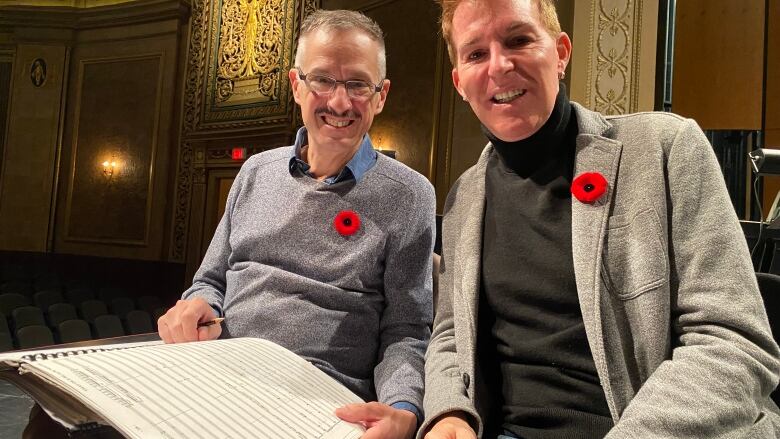 Two men sitting in theatre seats. The man on the left, Robert Franz, has a book of music on his lap.