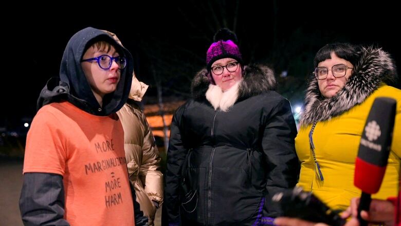 Four woman stand in a line while talking to a CBC reporter. 