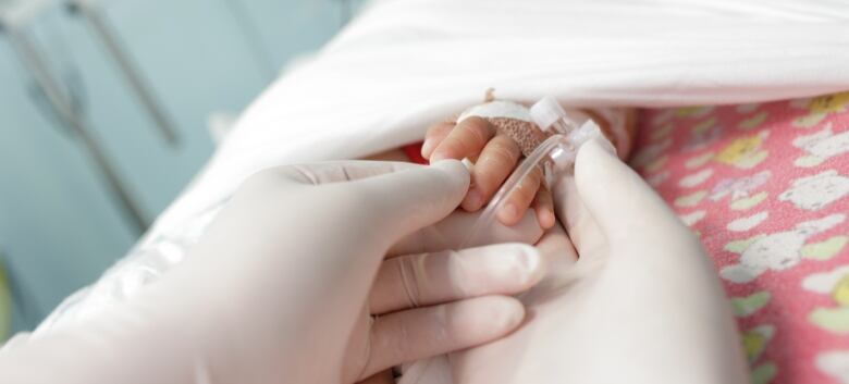 hands in gloves touches and holds hand a little sick child.