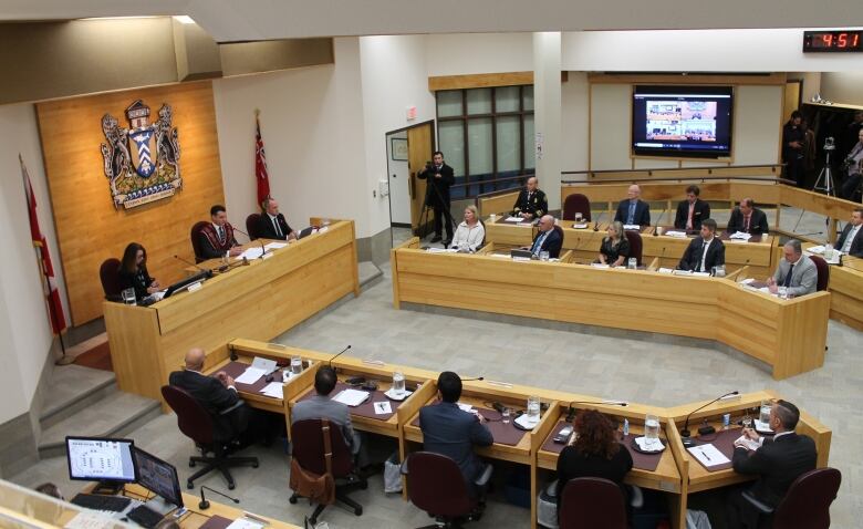 Overhead shot of Sault Ste. Marie council chambers, with ten councillors sitting and listening to the mayor speak 