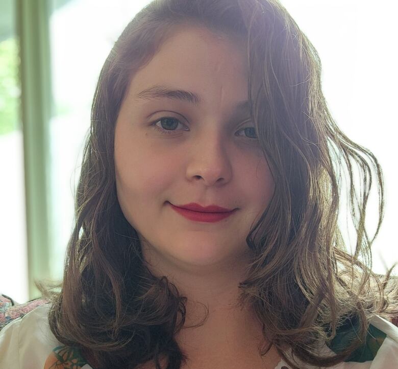 A young woman with long brown hair smiles at the camera.