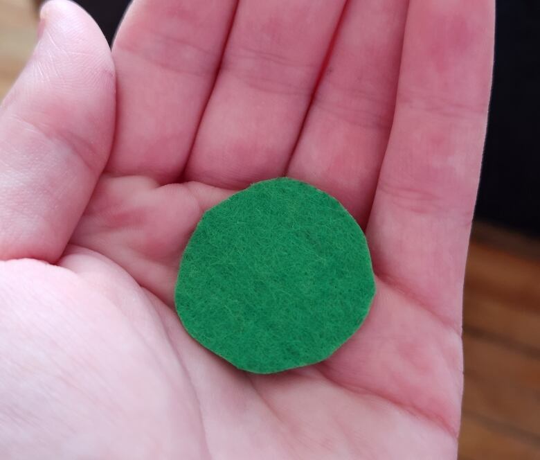 A closeup of a person's hand holding a small green felt circle.