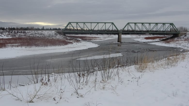 A bridge crosses a channel above gray and snowy water.