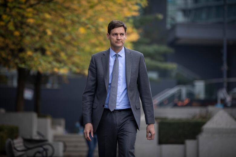 David Eby, a white man wearing a suit, walks through a plaza.