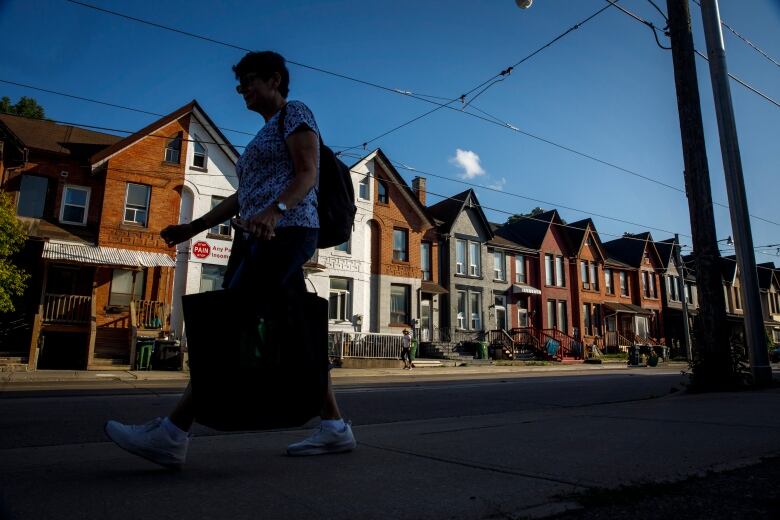 A person walks by a row of houses in Toronto on Tuesday July 12, 2022.The Association of Municipalities of Ontario says provincial housing legislation could leave communities short $5 billion - and taxpayers may have to foot the bill, either in the form of higher property taxes or service cuts.