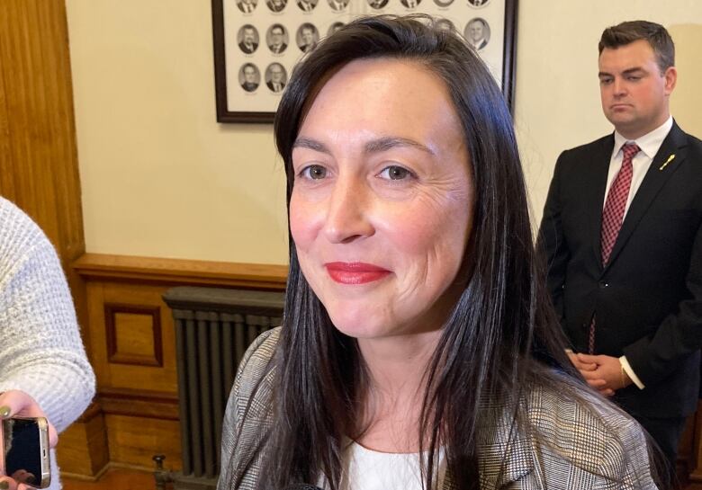 Woman with long brown hair standing in the lobby of the legislature.