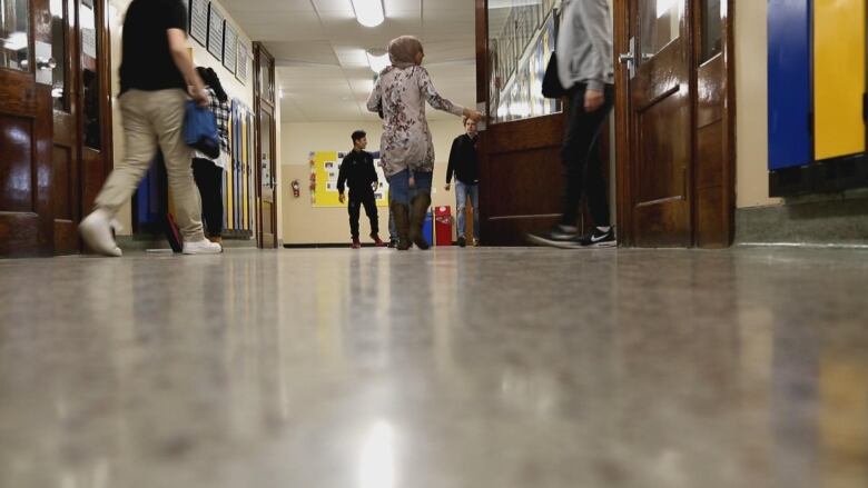 A school hallway where the feet of students walking are visible. 