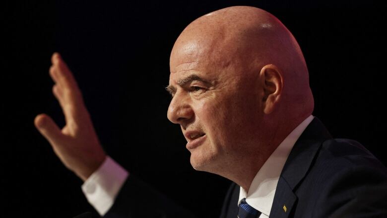 A side profile view of FIFA President Gianni Infantino, as he raises his hand while speaking.