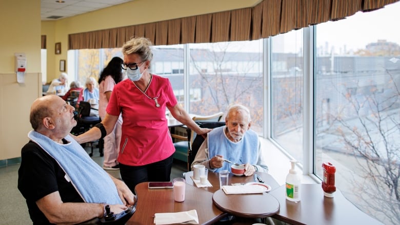 A nurse checking in on two residents of a long term care home.