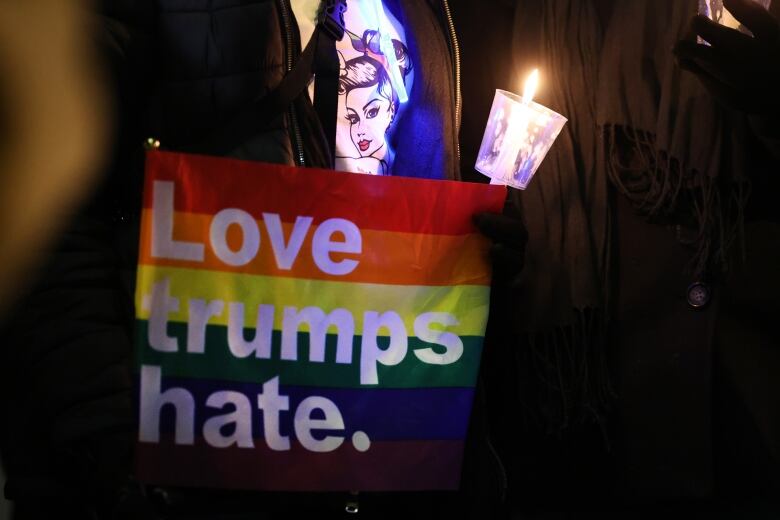 A woman holds a rainbow flag with a message on Monday night in Colorado Springs.  