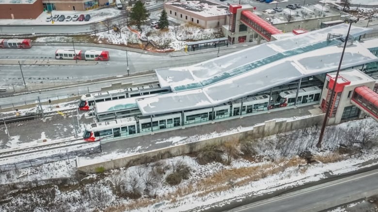 From above, two trains sit at a transit station in the snow.