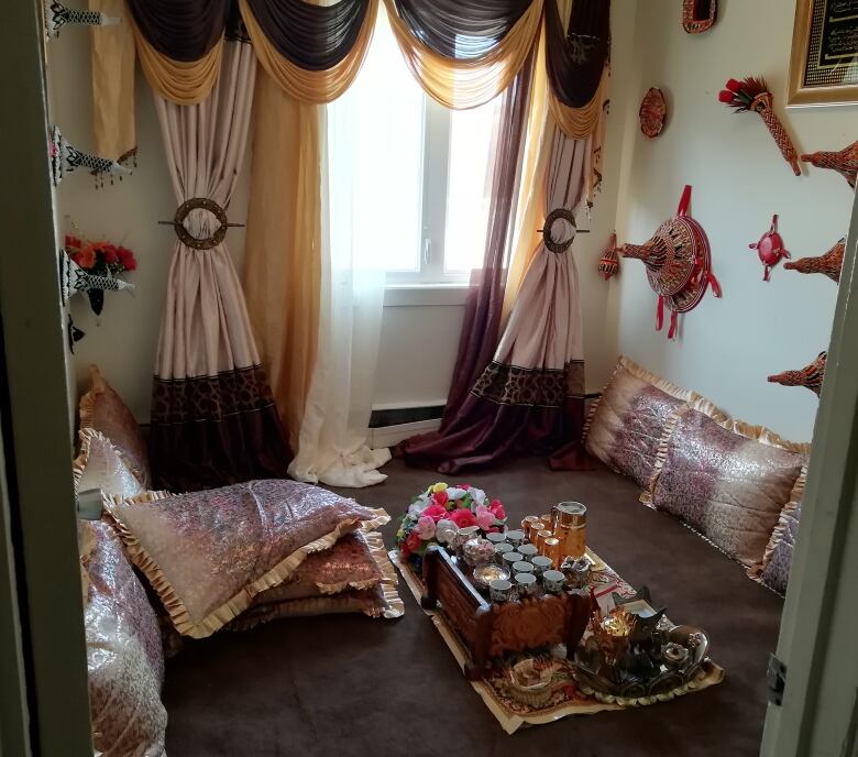 A bright room of pink drapes and cushions with a floor sofa, displaying traditional Ethiopian art. 