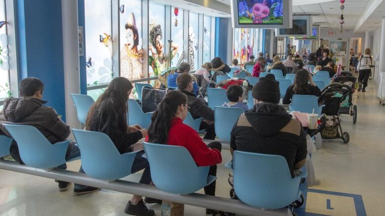 People sit in chairs in a hospital waiting room.