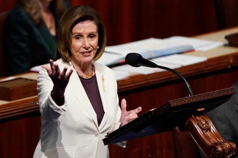 Nancy Pelosi stands behind a podium, speaking.