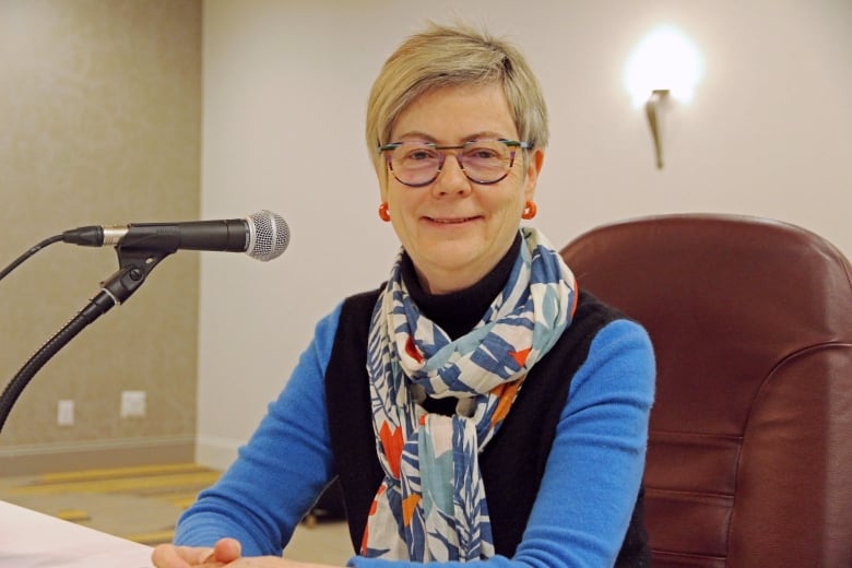 A woman with glasses and short hair smiles at the camera