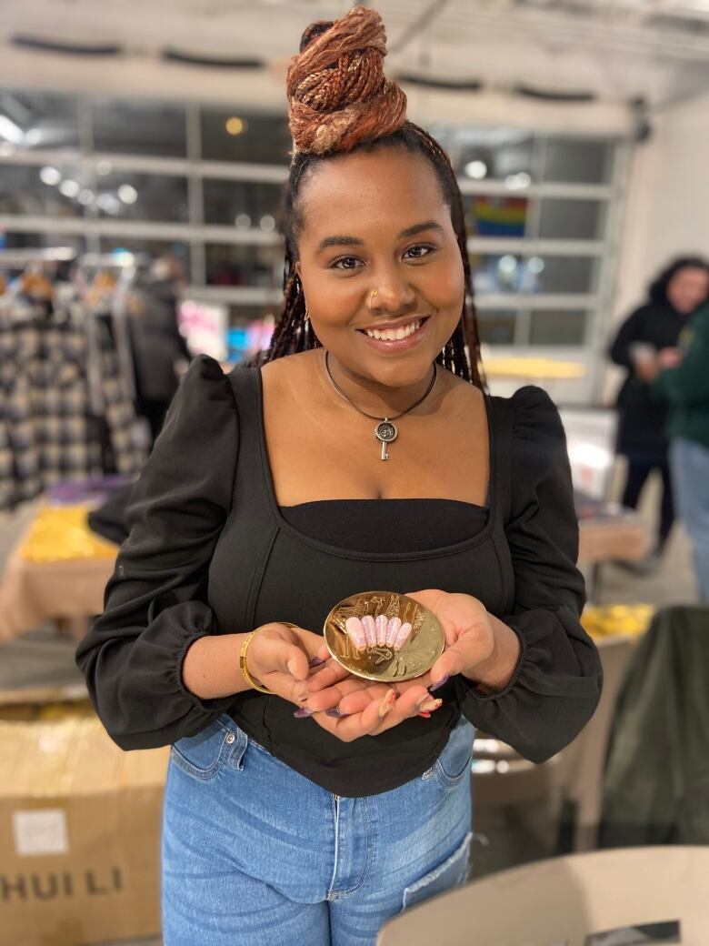 A woman holds custom jewelry she designed.