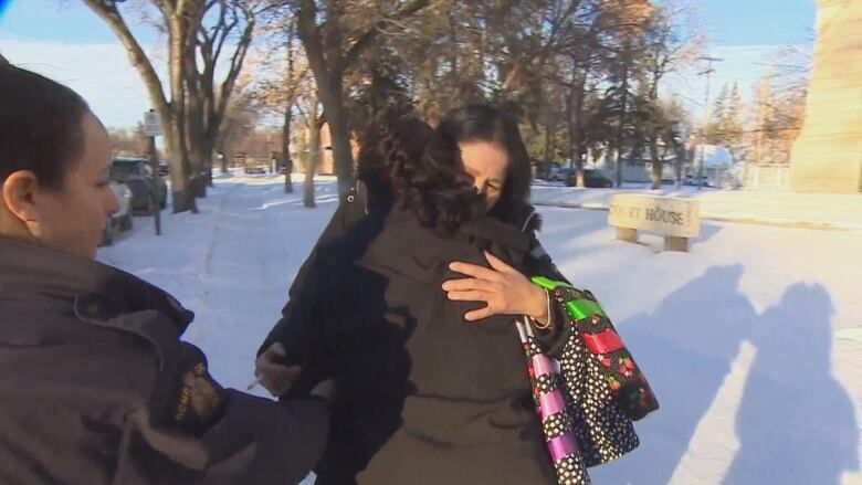 two women embrace, one in handcuffs