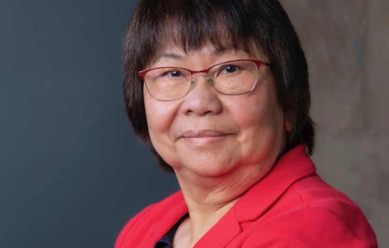 Lucy Reyes, dressed in red with glasses, looks into the camera.