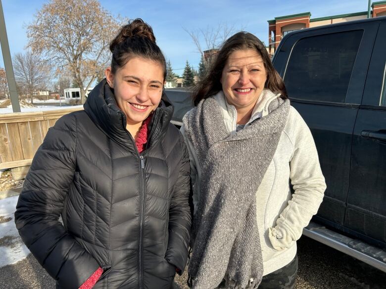 Two women wearing winter clothing are smiling at the camera.