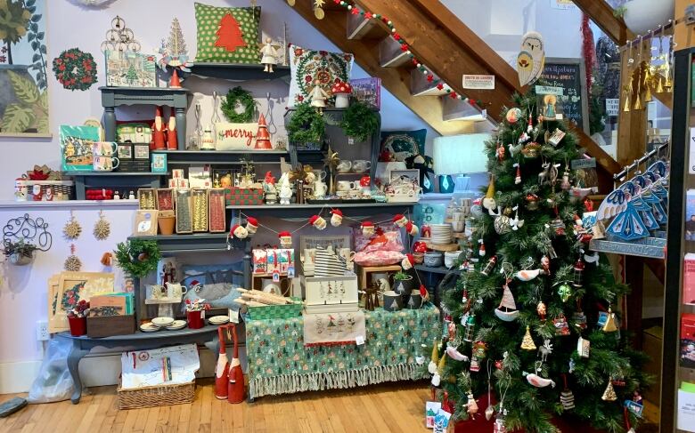 A display of Christmas products beside a Christmas tree covered in ornaments.