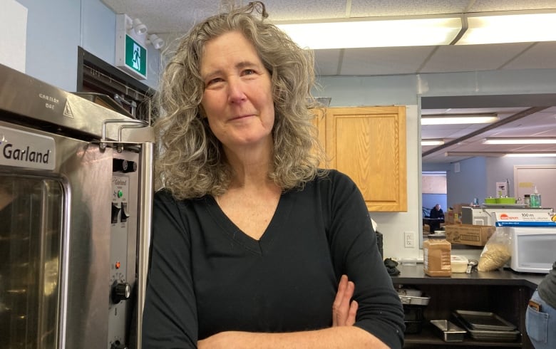 A woman stands for a portrait in a kitchen