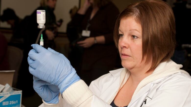 A female health-care professional prepares a dose of the influenza vaccine  