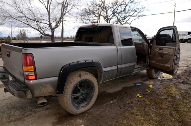 A truck with the passenger door open and exhibit markers on the ground near the truck.