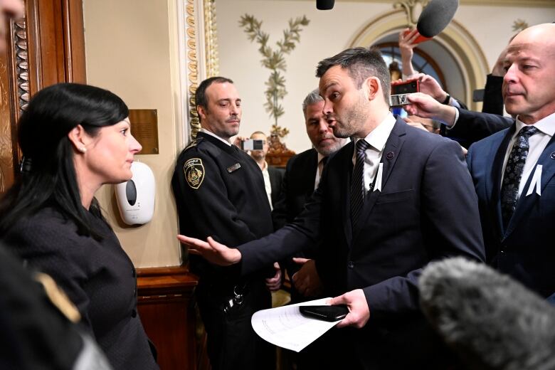 A woman confronts a man who holds a paper in his hand.