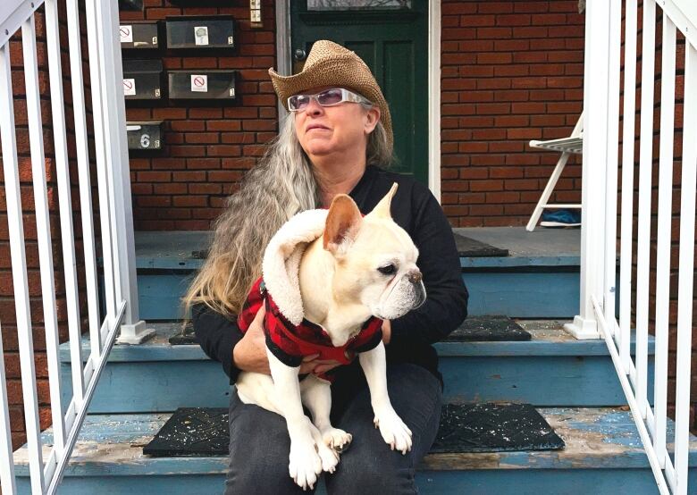 A woman on a stoop with a dog.