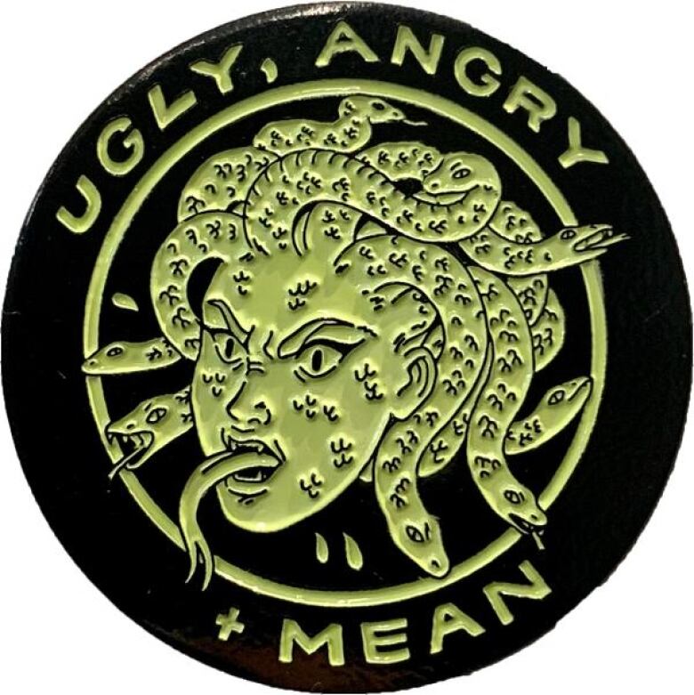 Round enamel pin. A cartoon gorgon is in the centre of the design. Text reading 