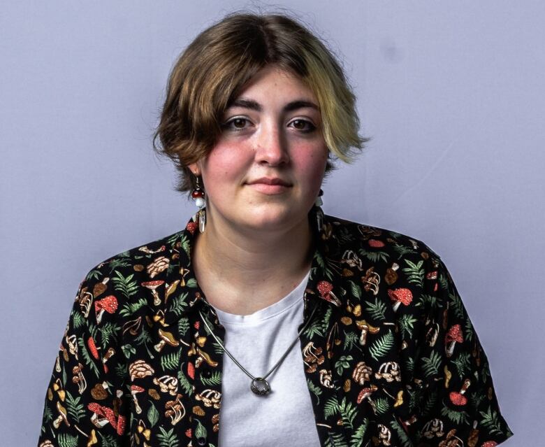 A young person in a patterned shirt poses and smiles slightly at the camera.