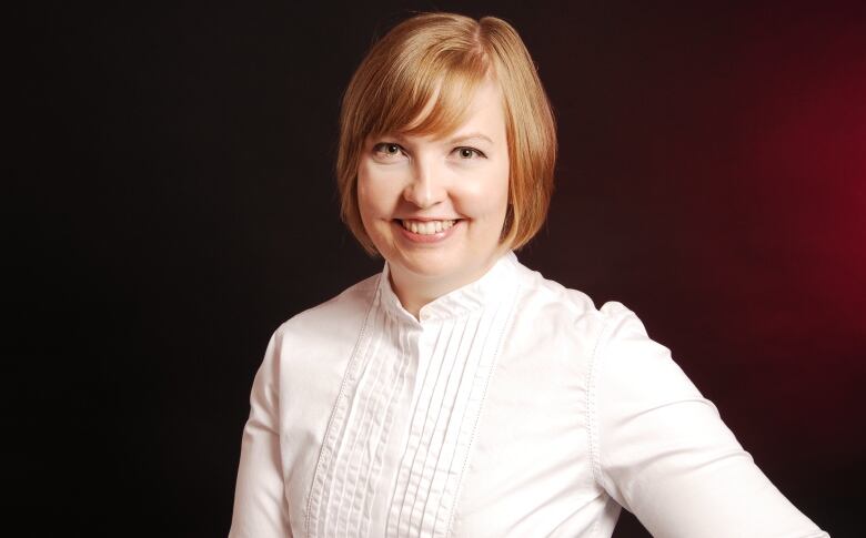 Jennifer Jackson is standing in front of a red background, wearing a white blouse, in this profile photo.