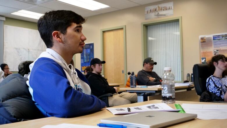 A young man listens to a lecture.