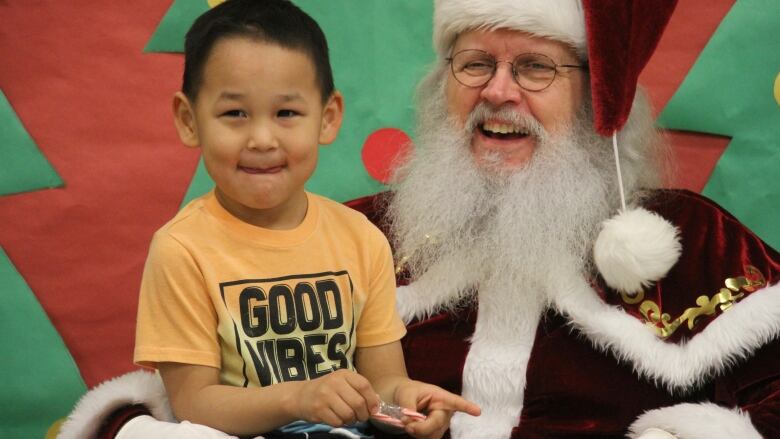 Santa Claus and a child grin at the camera.