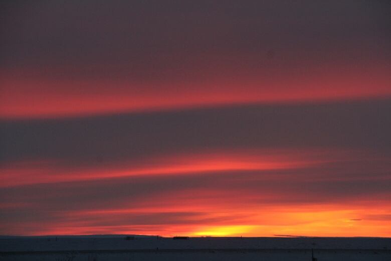 A scenic shot of the sun rising against vivid red skies