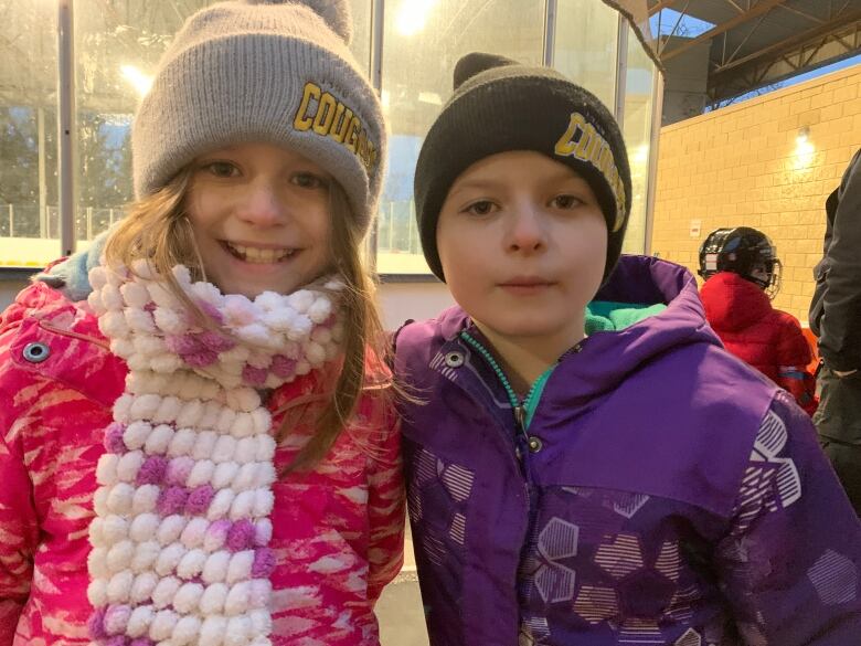 Twins stand in front of an ice rink 