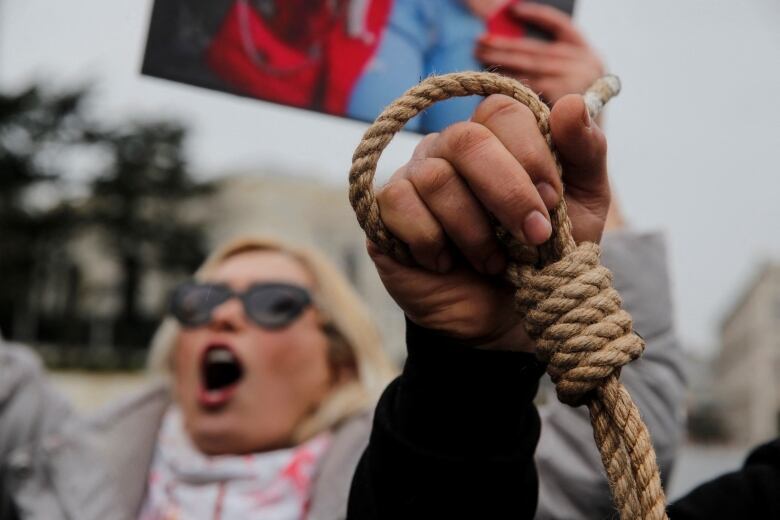 A fist holds up a noose during a protest