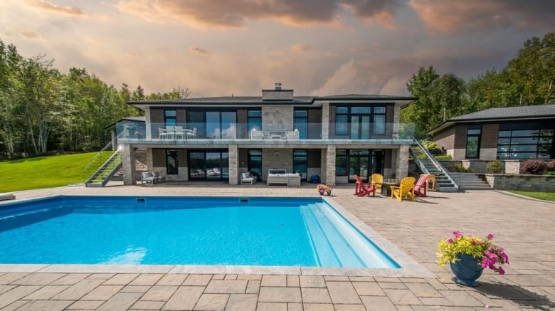 A rectangular swimming pool with a house behind it.