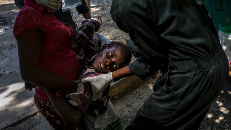 A youth suffering from cholera is helped upon arrival at a clinic run by Doctors Without Borders in Port-au-Prince, Haiti, on Oct. 27, 2022.