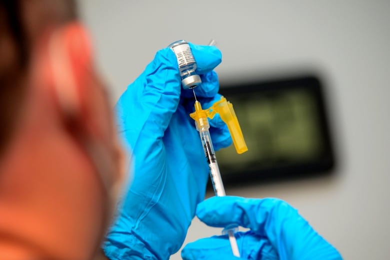 A health-care worker prepares a dose of Pfizer's bivalent COVID-19 vaccine.