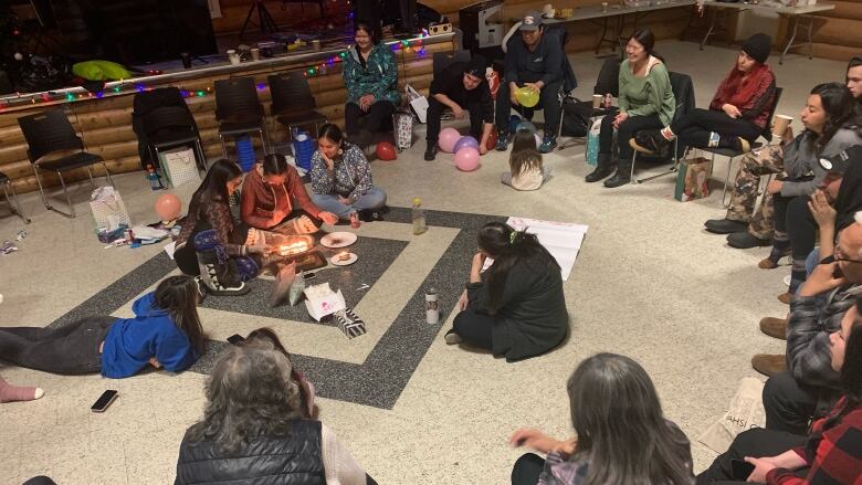 A semi-circle of seated people, gathered around a traditional qulliq lamp.