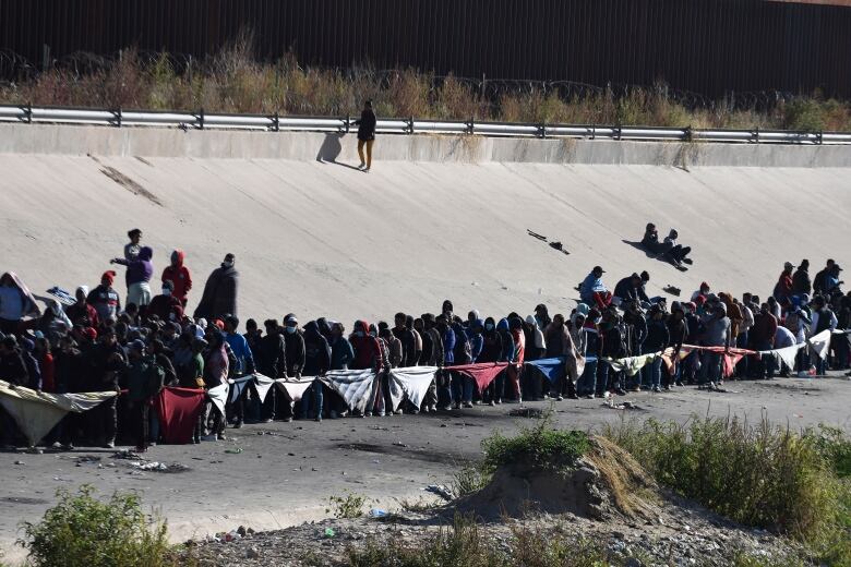 Migrants stand in a line at the U.S.-Mexico border.