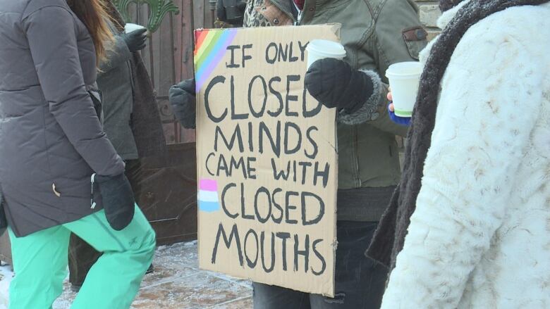 A protester in a crowd holds a sign saying 